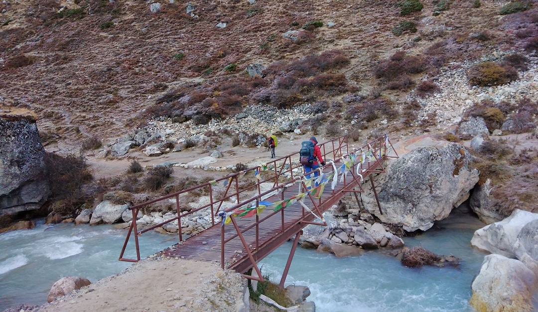 Trekker crossing a bridge near Pheriche